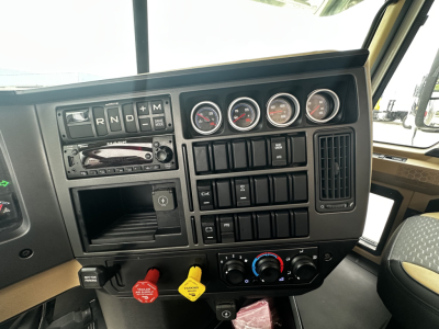 Dashboard view of a 2026 Mack PI64 cab and chassis showing gear selector, multiple gauges, switches, and climate controls.