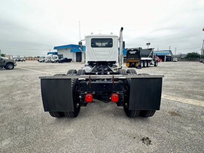 Truck cab and chassis rear view showing dual rear wheels, fifth wheel area, and red hydraulic/brake components; no visible text on components in this angle.
