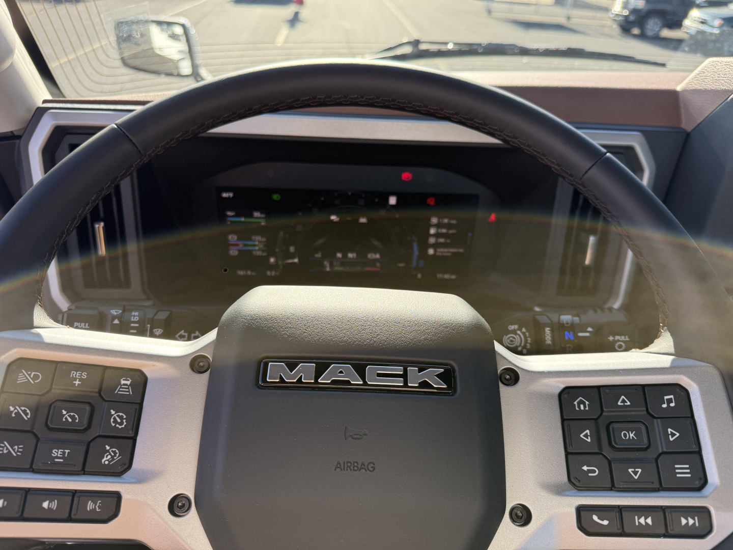 Mack PR64T dashboard steering wheel view showing Mack logo and instrument cluster.