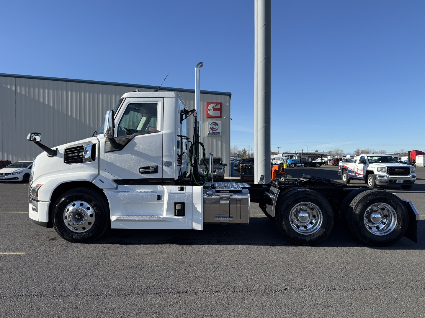 Truck side view showing Mack PR64T cab-over-engine tractor with chrome fuel tanks and dual rear axles. Visible text on cab area includes no legible brand markings beyond Mack design.