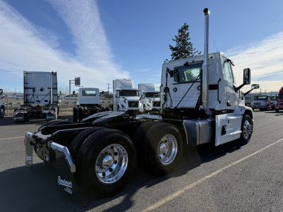 Truck chassis view of a 2026 Mack PR64T conventional daycab showing dual rear axles and chrome wheels. 