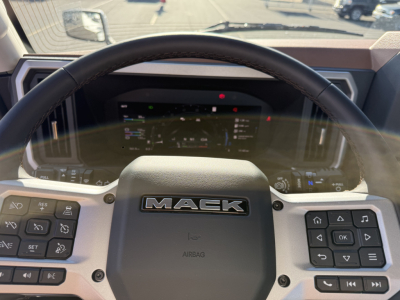 Mack PR64T dashboard steering wheel view showing Mack logo and instrument cluster.