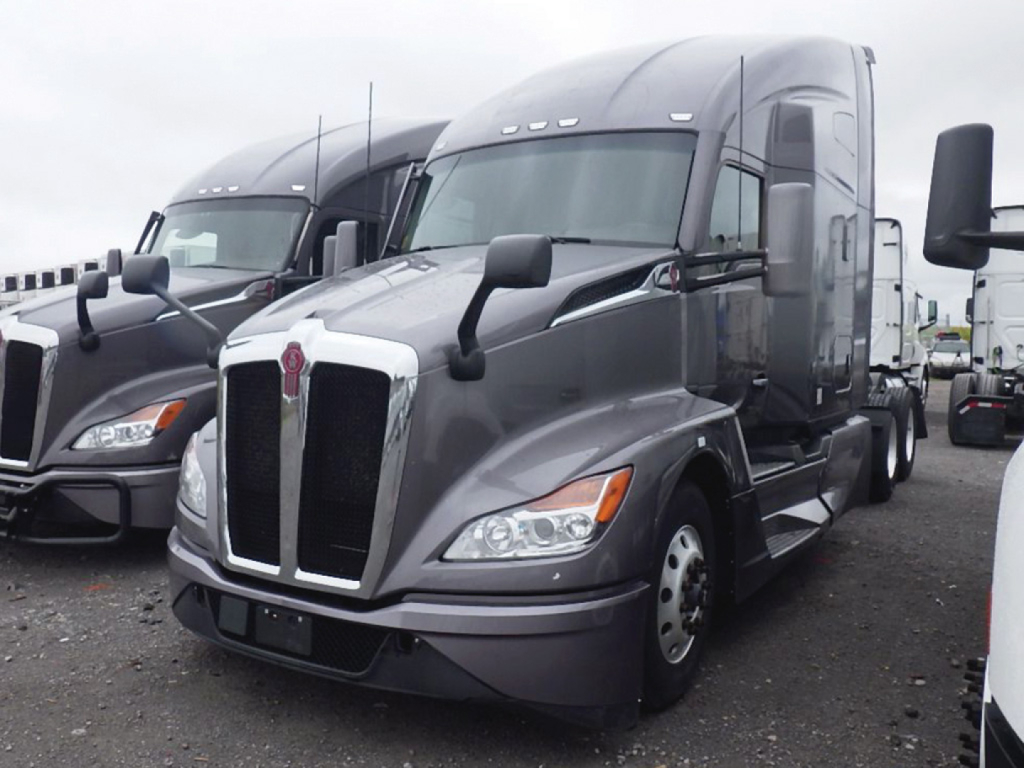 Kenworth T-680 Next Gen tractor in a truck lot, gray exterior, front view.