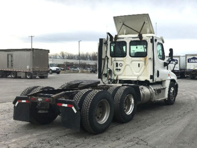 Semi tractor in sideloaded view showing rear axles and fifth-wheel mount for Freightliner Cascadia125 with white cab and dual rear tires.