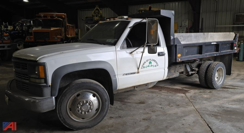 Chevrolet CK 3500HD dump bed truck in a workshop showing side view with dual rear wheels and dump box