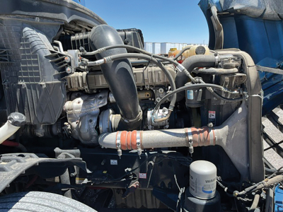 Truck engine bay of a 2020 Freightliner Cascadia126 showing engine components, hoses, and air filter housing.