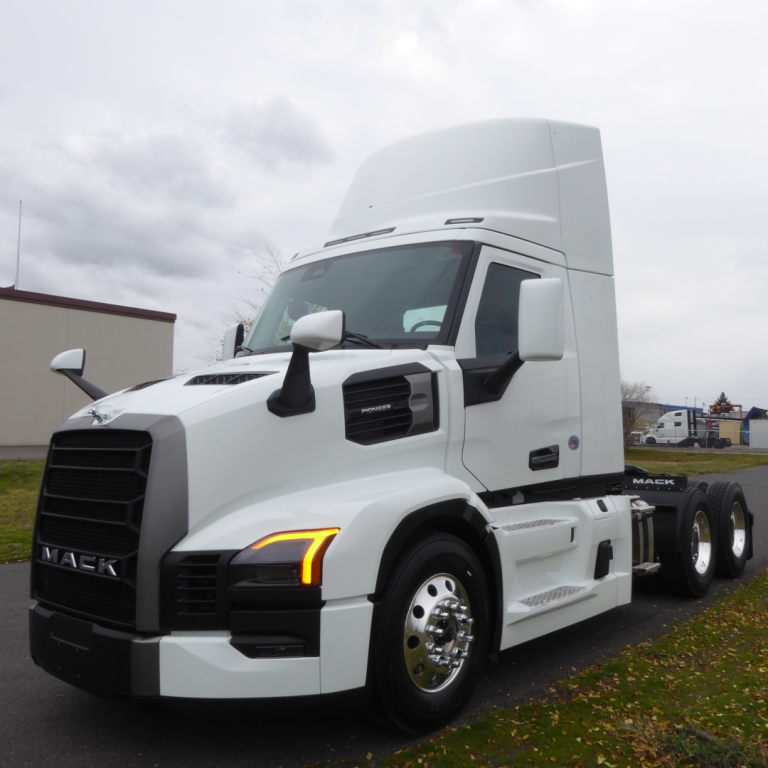 Mack PR64T truck in white front-left view showing cab with aerodynamic sleeper and dual rear axles.