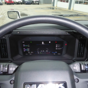 Dashboard view of a 2026 Mack PR64T truck showing digital gauge cluster, steering wheel with Mack logo, and side mirrors.