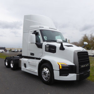Mack PR64T tractor-trailer cab in white, side view showing front grille, headlights with amber indicators, tall aerodynamic sleeper, wheels, and exhaust area.