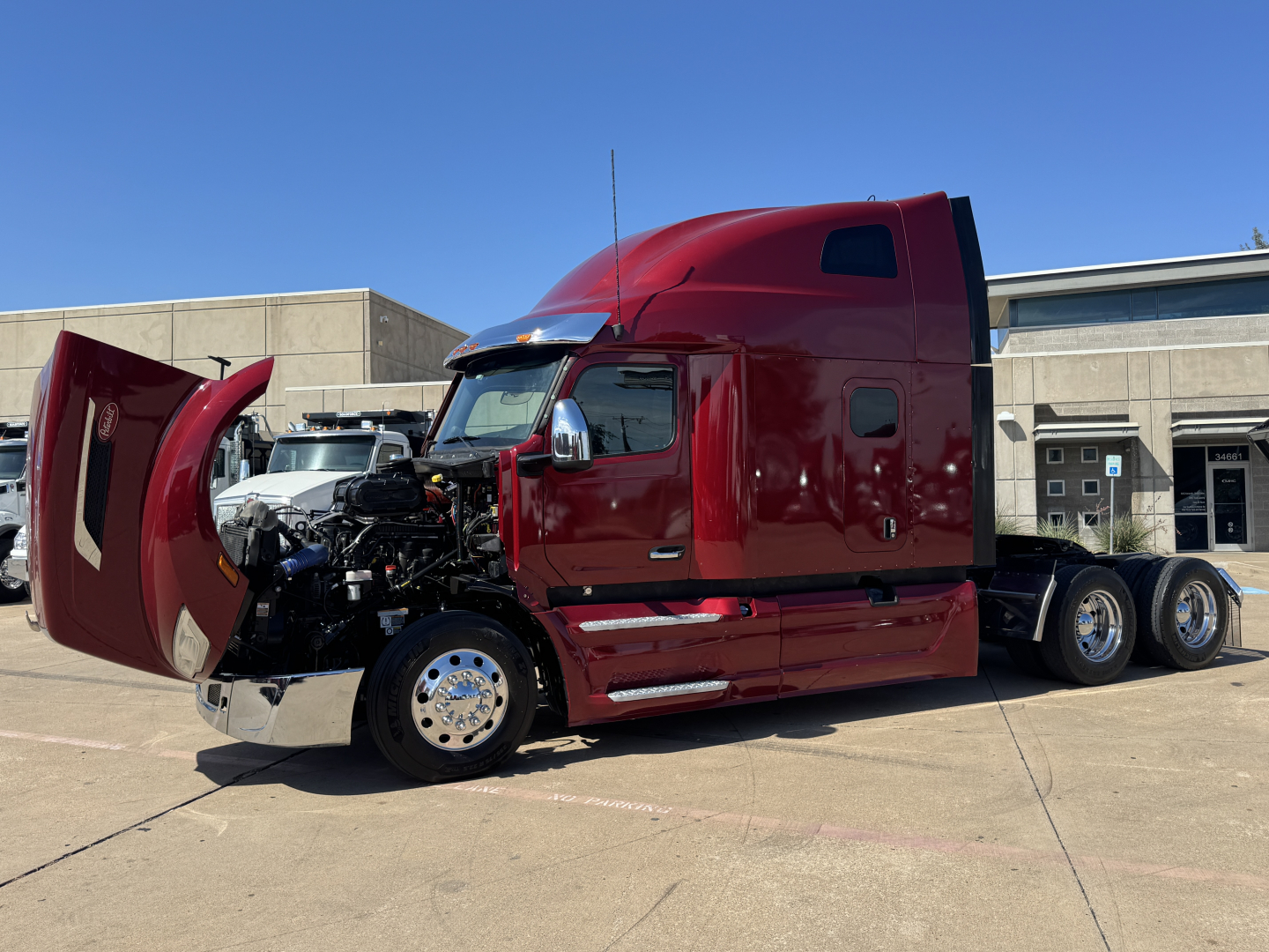 Peterbilt 579 conventional sleeper truck in red with hood open exposing engine bay and front wheels. Side view shows dual rear axles and cab doors closed.