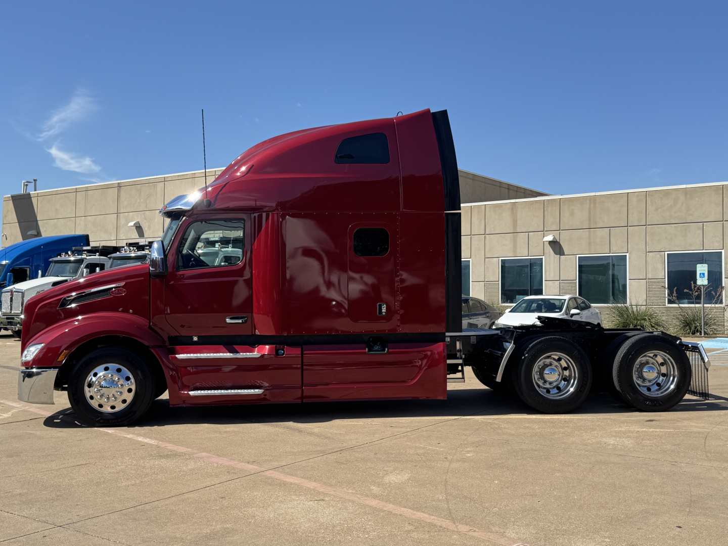 Peterbilt 579 conventional sleeper truck in red parked outside; side view shows cab with aerodynamic sleeper, chrome wheels, and dual rear axles.
