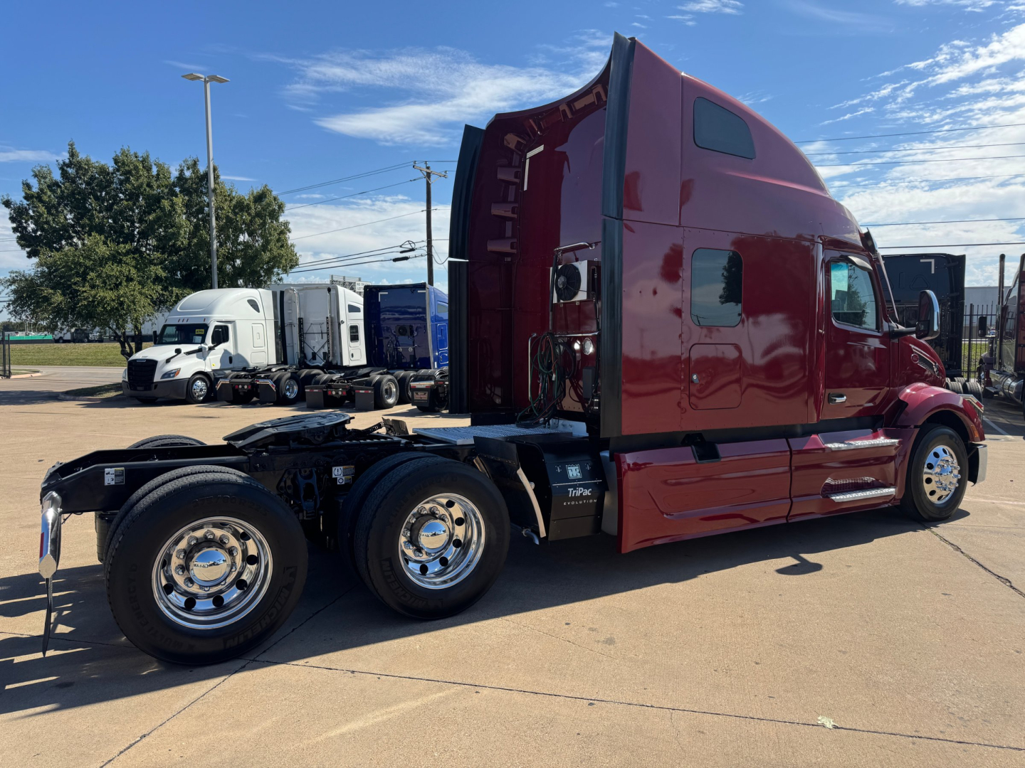 Peterbilt 579 tractor cab in maroon color, side view showing sleeper, rear wheels, and chassis without trailer. VIN sticker and stock number not visible, front and side windows visible.