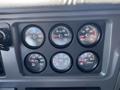Peterbilt 579 dashboard gauges showing multiple analog meters including front axle, rear, and oil temperature; text on gauges partially legible.