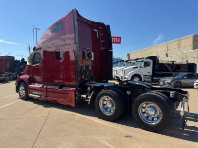 Peterbilt 579 tractor-trailer side view showing deep red cab and chassis with sleeper cab, chrome wheels, and fifth wheel hitch.