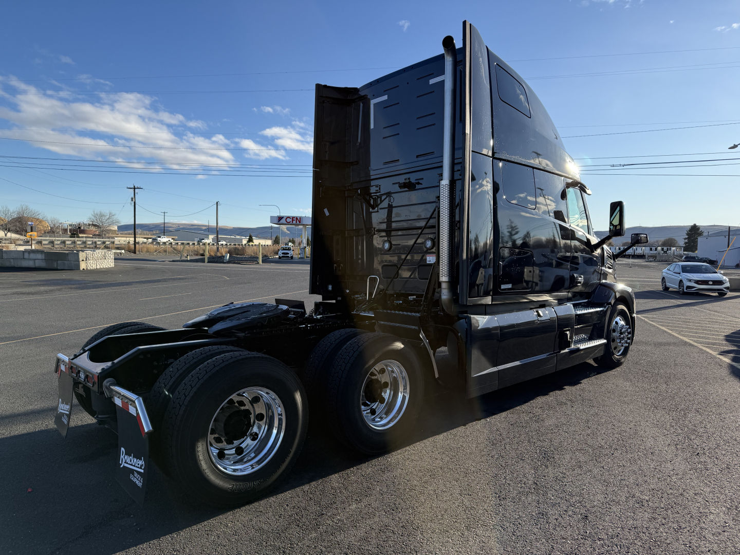 Truck sleeper cab chassis side view showing rear dual axles and tall aerodynamic sleeper in black with chrome wheels.