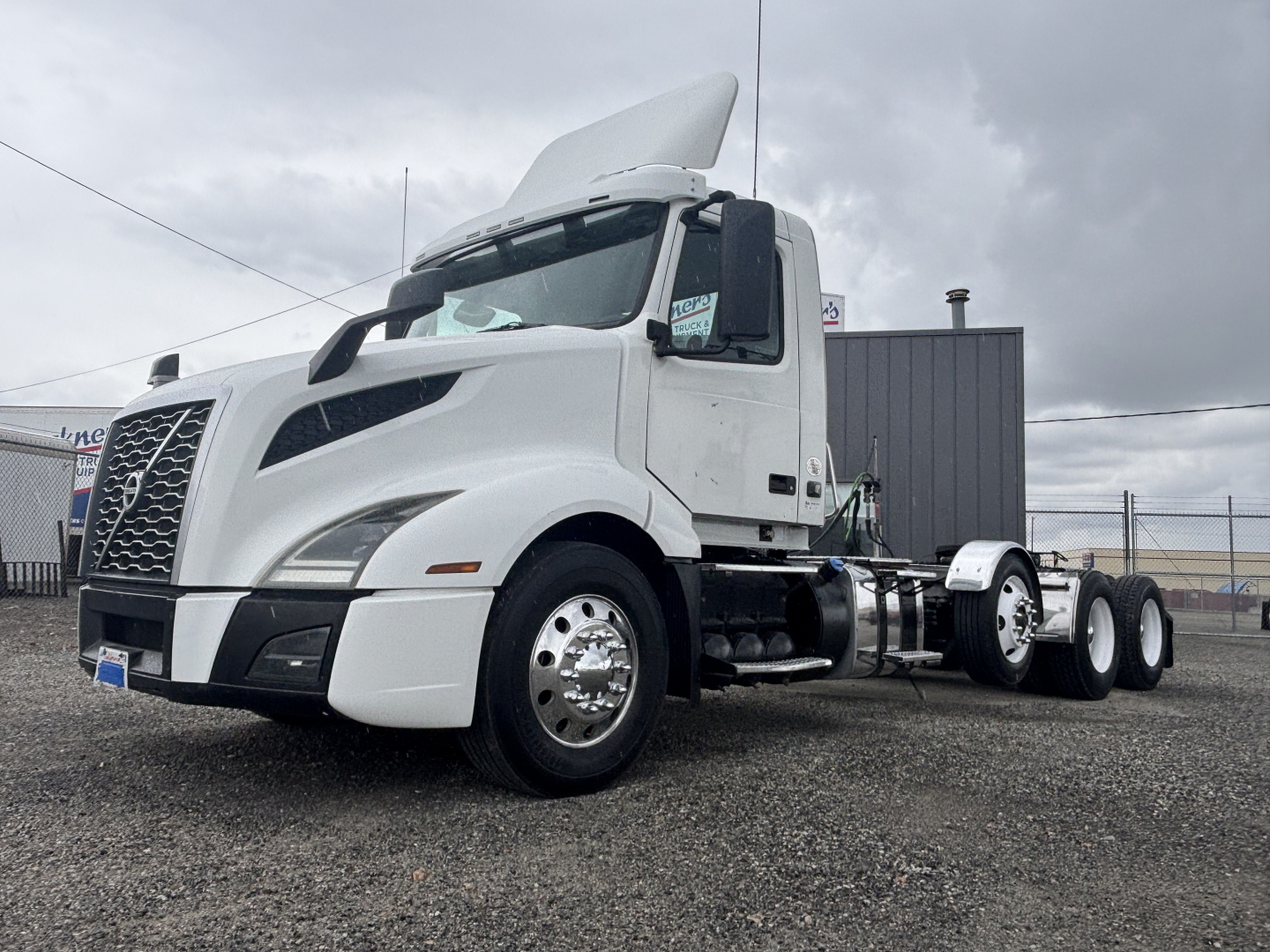 Volvo VNL84T300 daycab tractor truck in white, left front view with hood open showing cab and chassis.