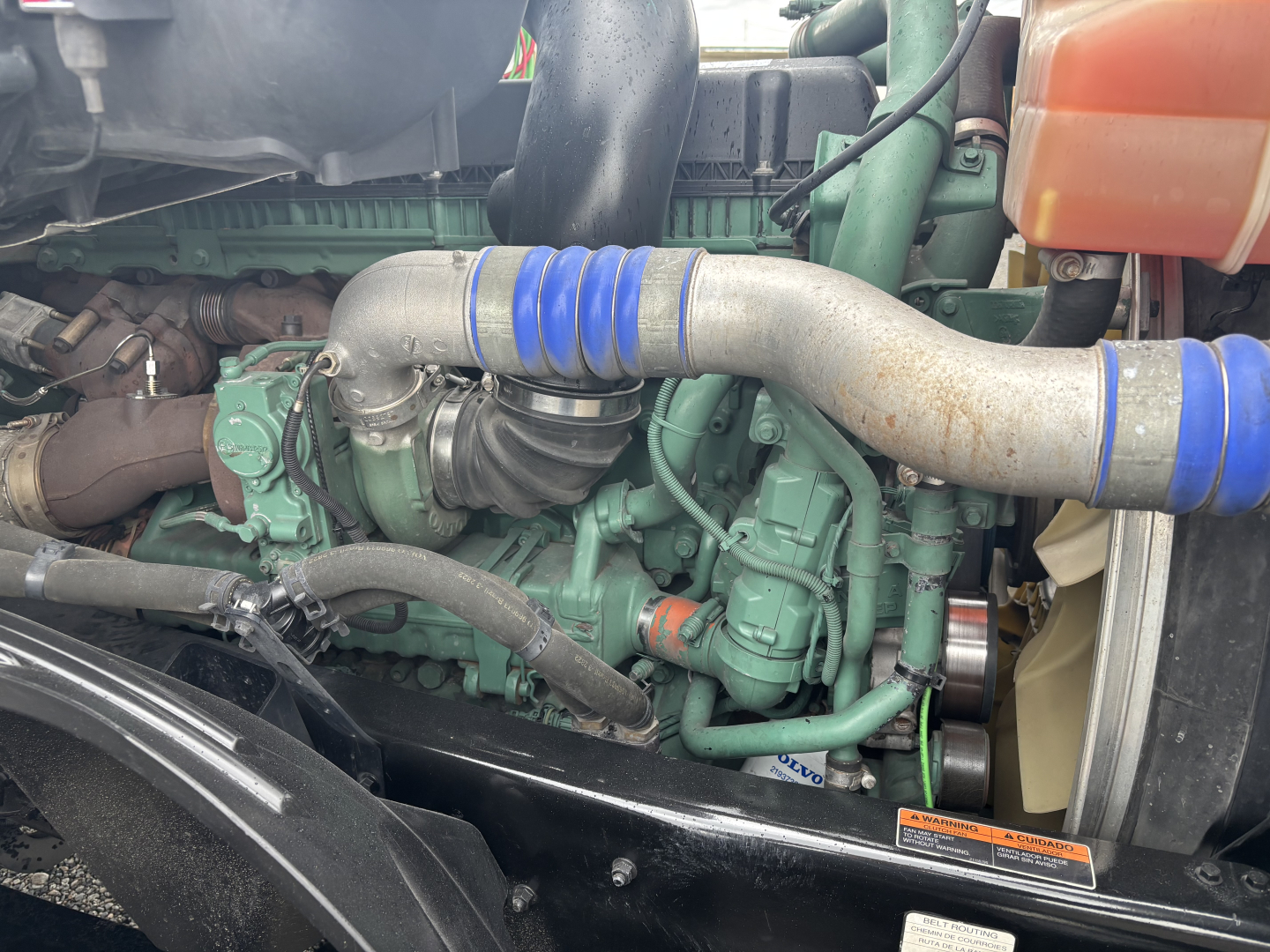 Volvo VNL84T300 engine bay showing intake hose with blue couplings, green engine block, and surrounding components.