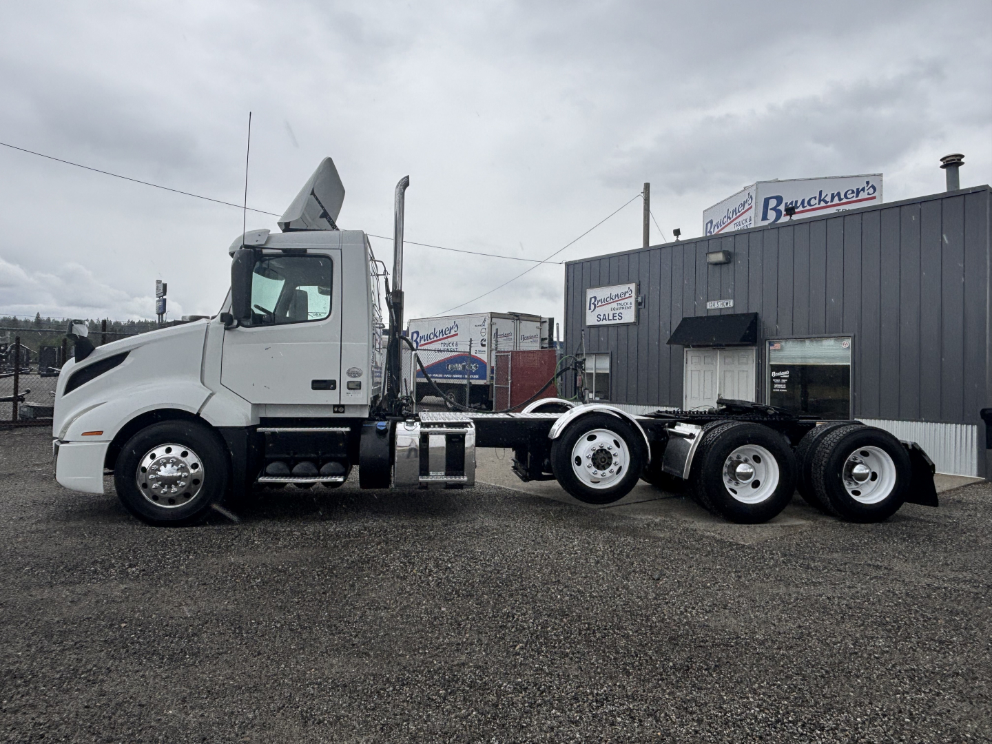 Volvo VNL84T300 tractor in a dealership lot, side view showing chassis and tandem rear axles; no visible text on the truck from this angle.