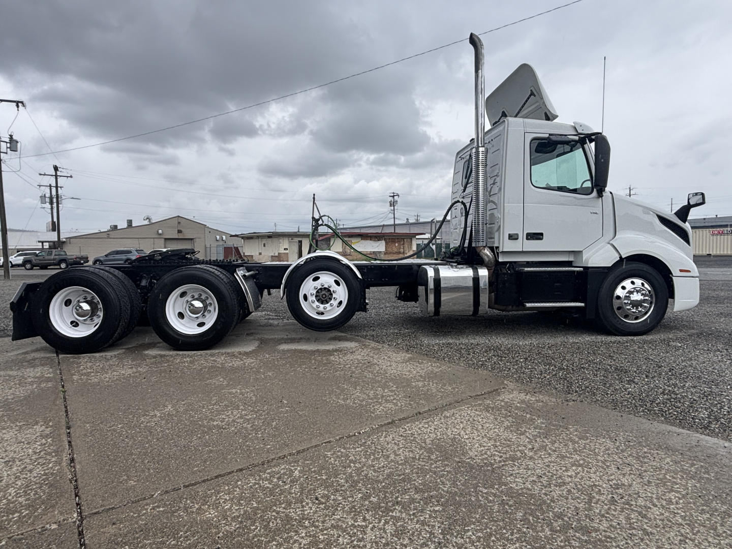 Volvo VNL84T300 tractor-trailer in service showing side profile with sleeper cab and dual rear axles, white paint, chrome exhaust stack.