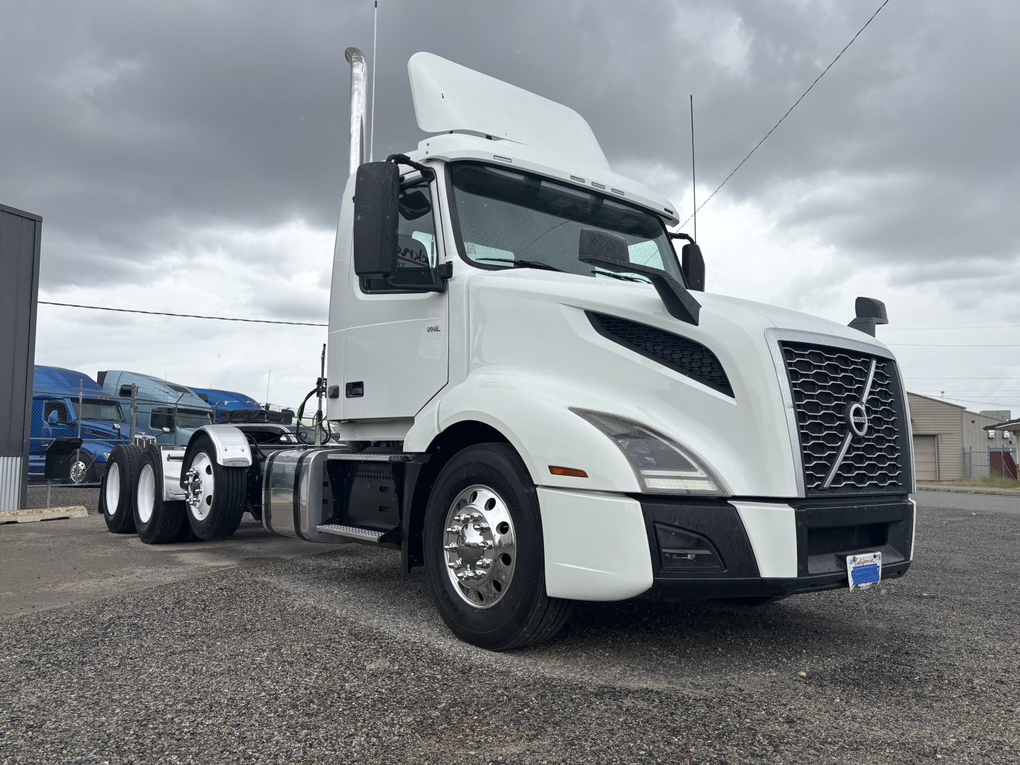 Volvo VNL truck front-right view showing cab and grille, white exterior, large Volvo emblem on grille, windshield, side mirrors, and front bumper.