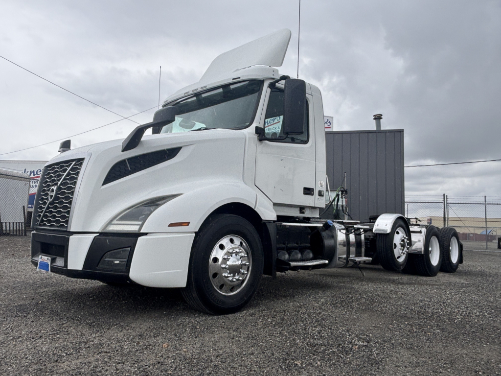 Volvo VNL84T300 daycab tractor truck in white, left front view with hood open showing cab and chassis.