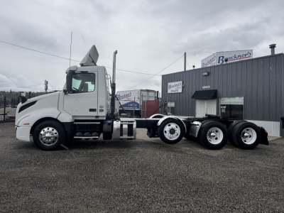 Volvo VNL84T300 tractor in a dealership lot, side view showing chassis and tandem rear axles; no visible text on the truck from this angle.