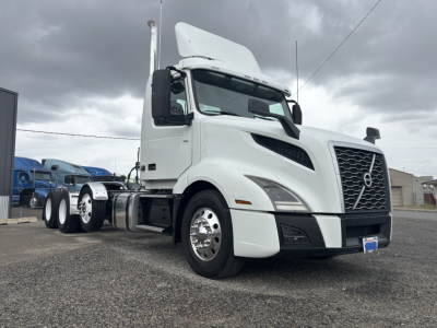 Volvo VNL truck front-right view showing cab and grille, white exterior, large Volvo emblem on grille, windshield, side mirrors, and front bumper.