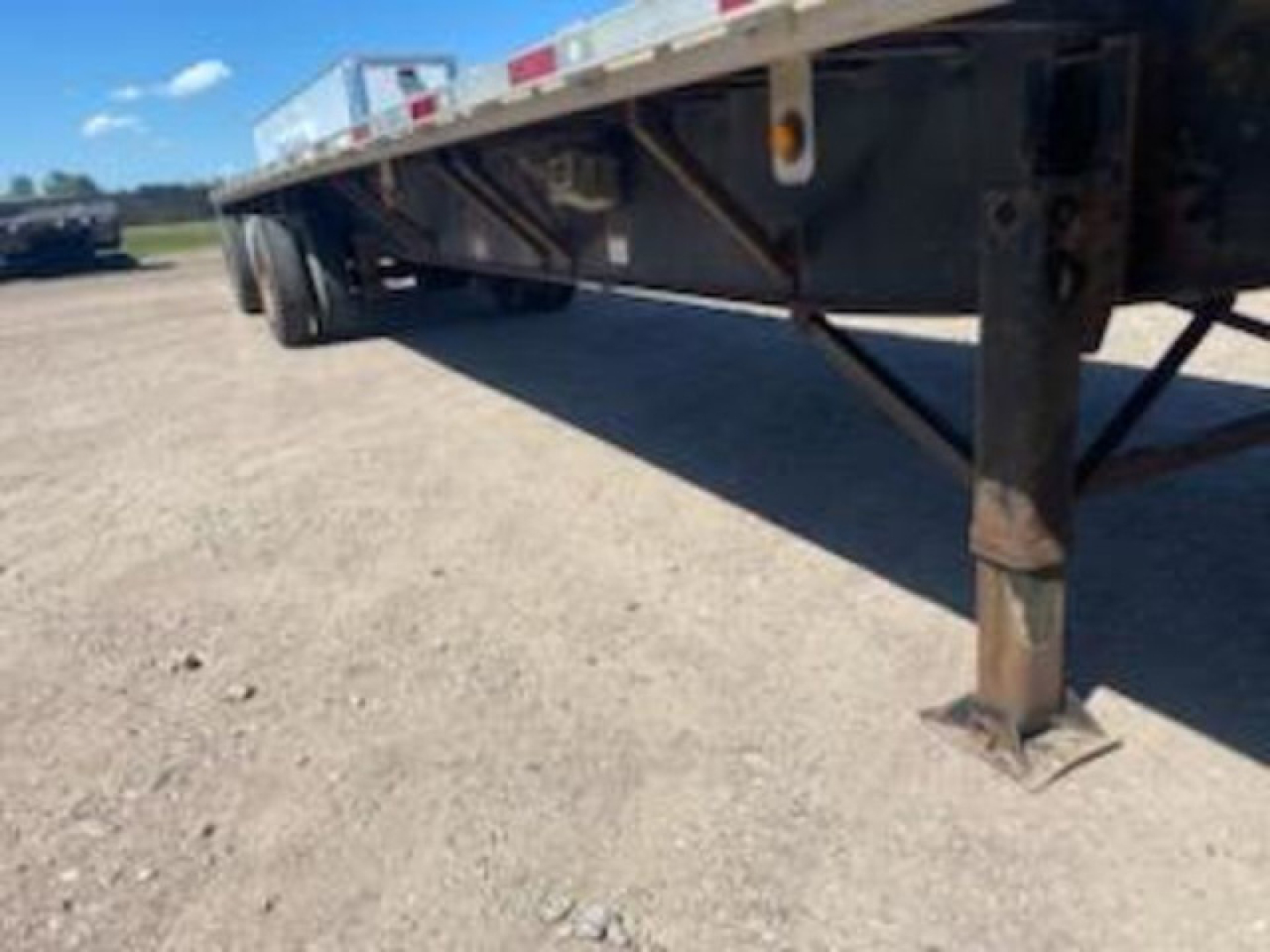 Trailer undercarriage with support leg and frame showing structural cross braces and wheel area of a utility flatbed trailer.