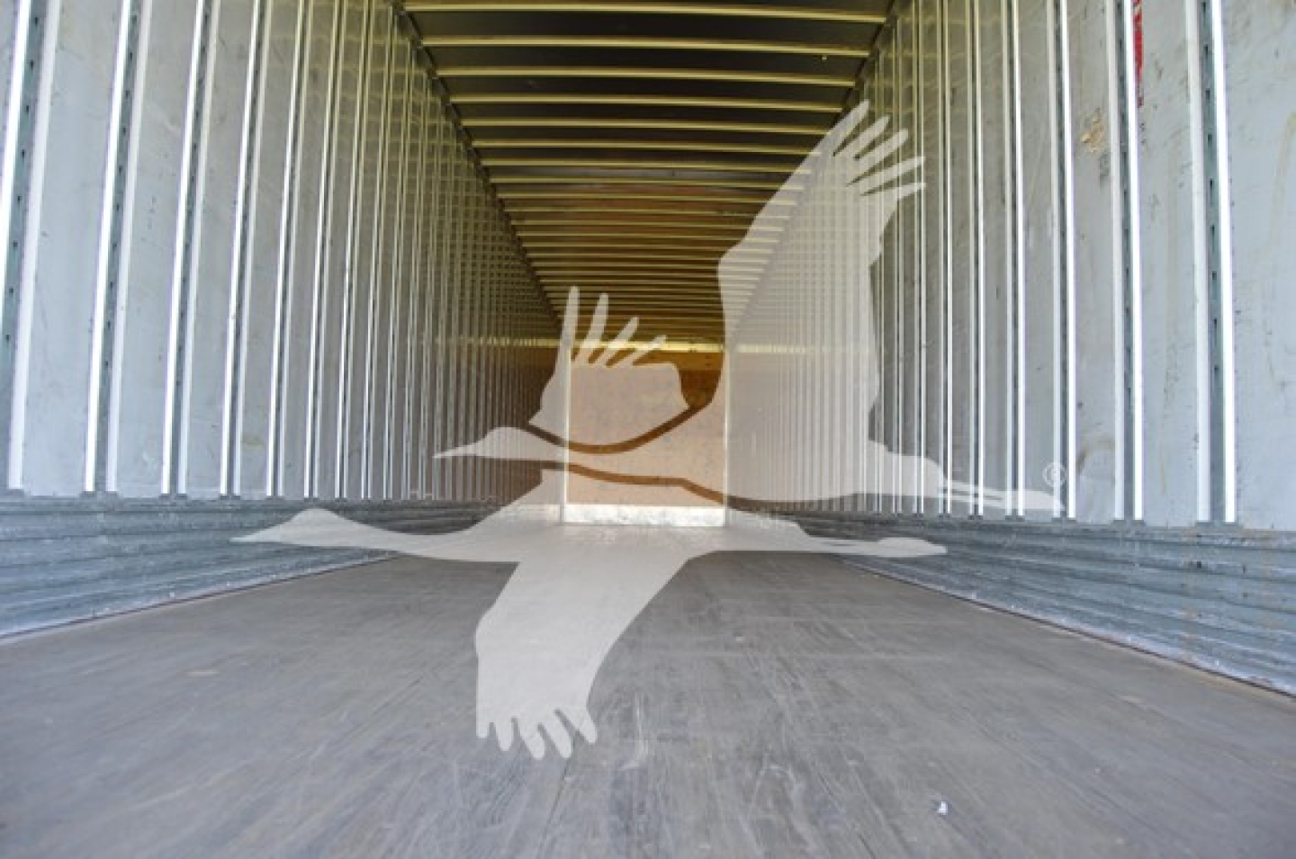 Interior view of a utility trailer with metal walls and a wooden/metal floor, empty cargo space.