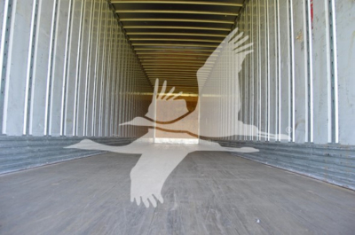 Interior view of a utility trailer with metal walls and a wooden/metal floor, empty cargo space.