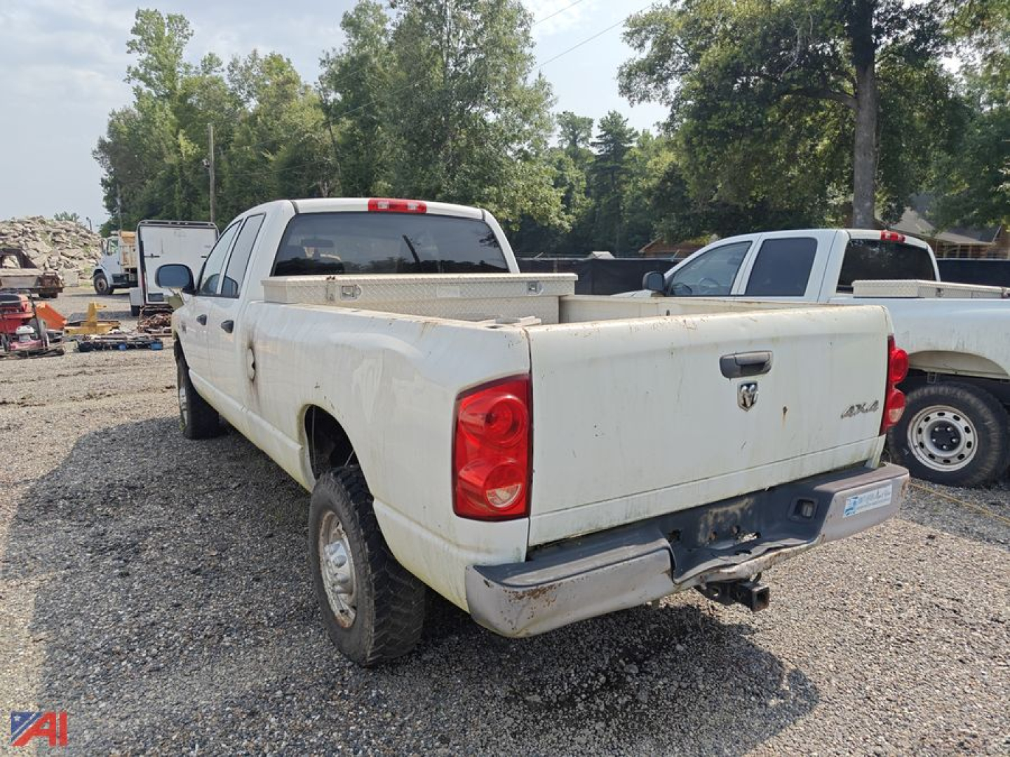 Dodge Ram 2500 pickup truck rear view showing cargo bed and tailgate with tow hitch in a gravel lot.