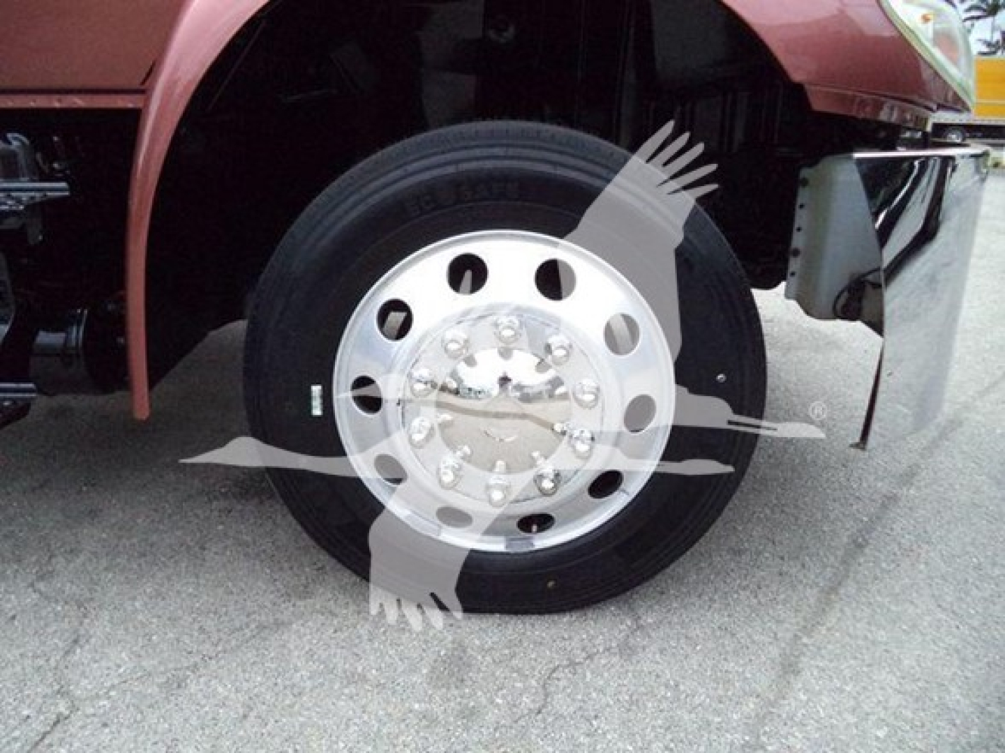 Truck front wheel showing polished steel rim and tire with hub and suspension components visible
