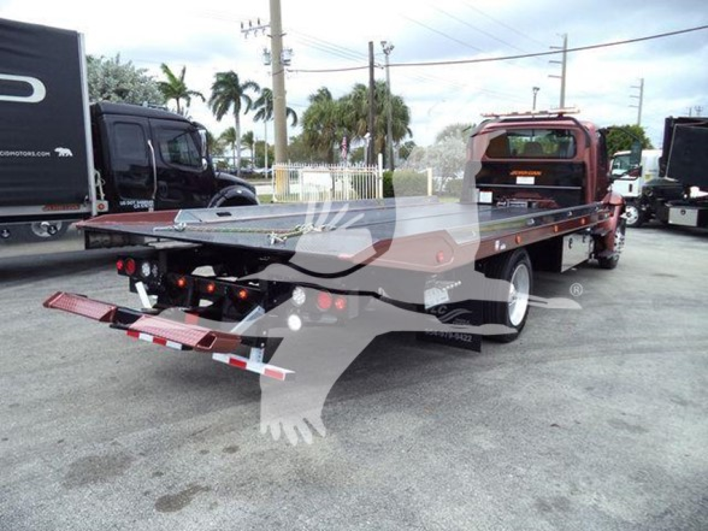 Truck bed rollback tow truck with flatbed and ramps visible.