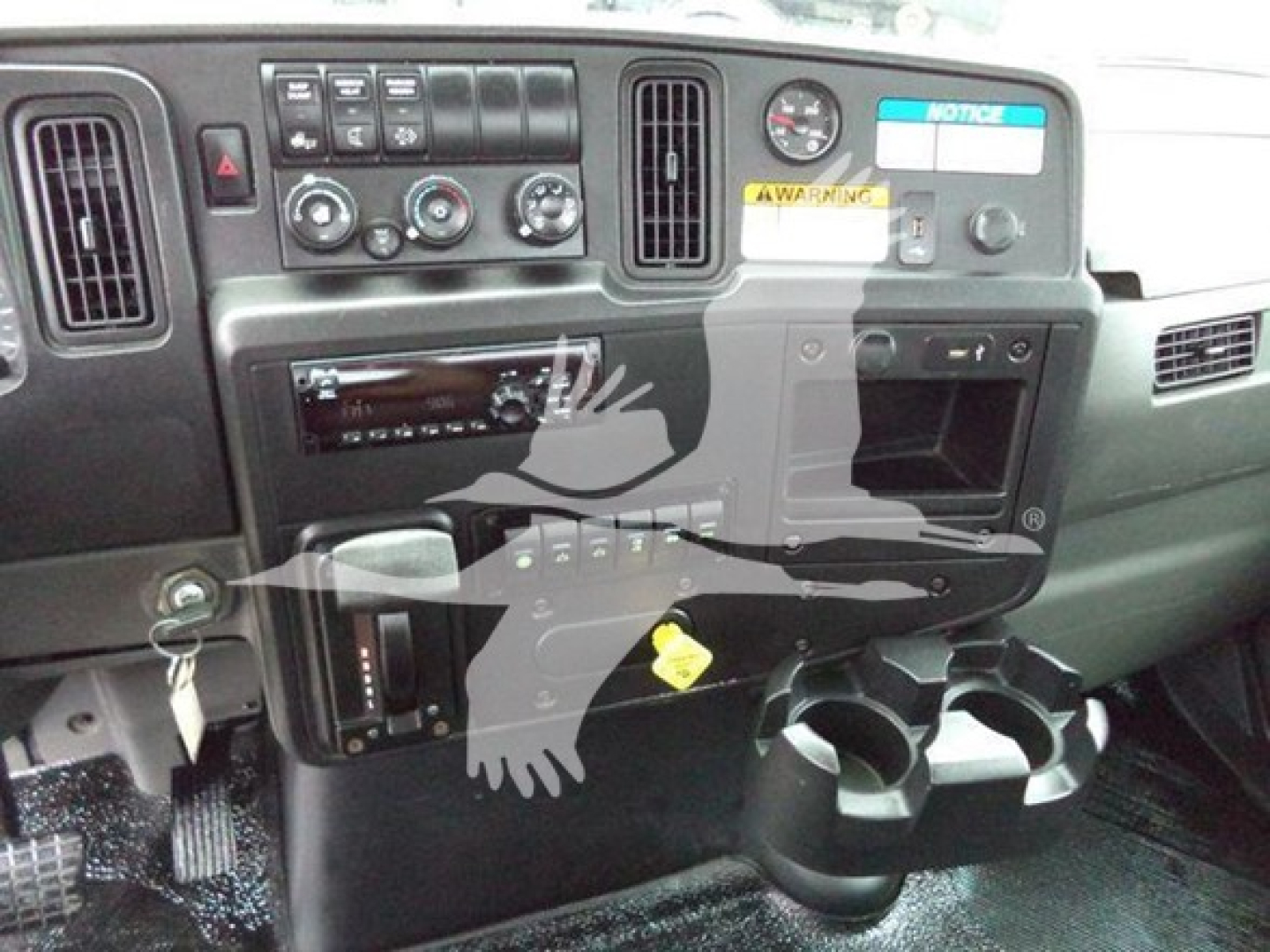 Dashboard of a 2020 International MV rollback truck showing instrument cluster, climate controls, radio, cup holders, and warning labels.