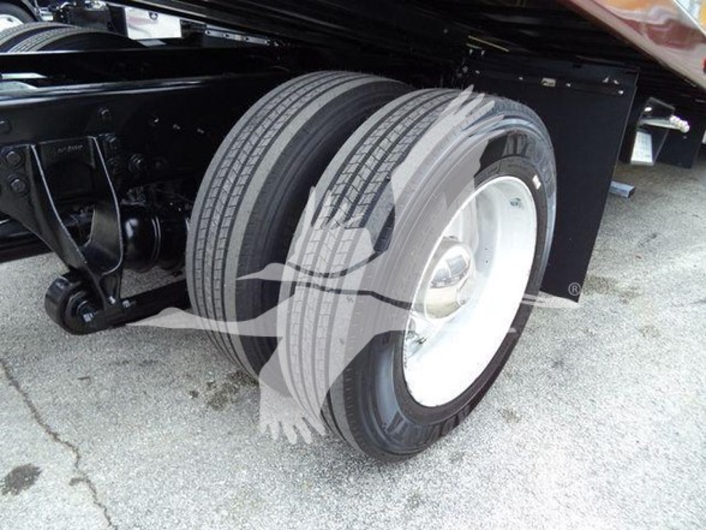 Truck rear dual wheels assembly showing white steel rims and dual tires on a rollback chassis, undercarriage with suspension and frame components visible.
