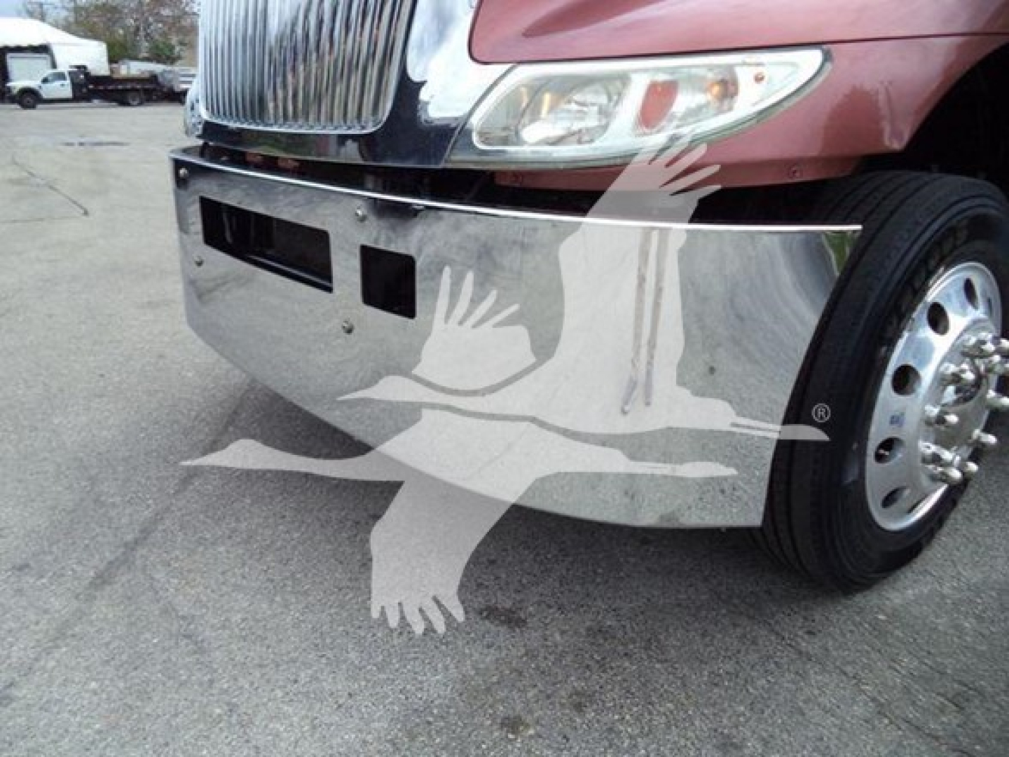 Vehicle front bumper of a red International truck with chrome bumper and wheel visible.