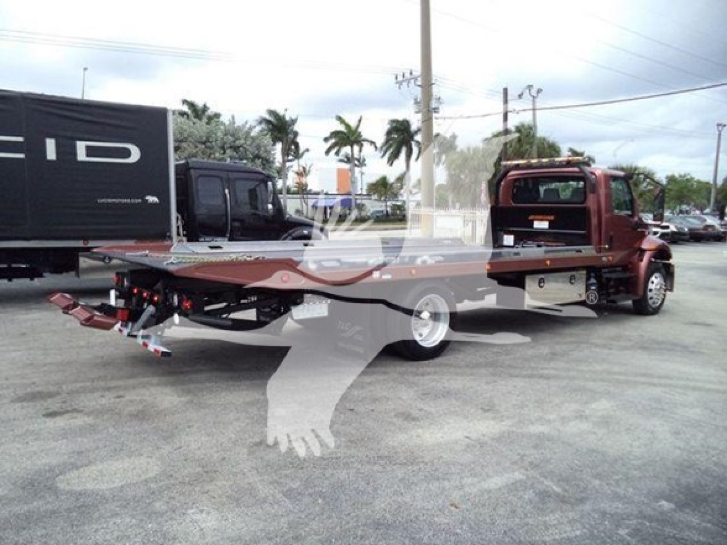 Truck wrecker/rollback tow truck side view showing flatbed, rear hitch, and dual rear wheels.
