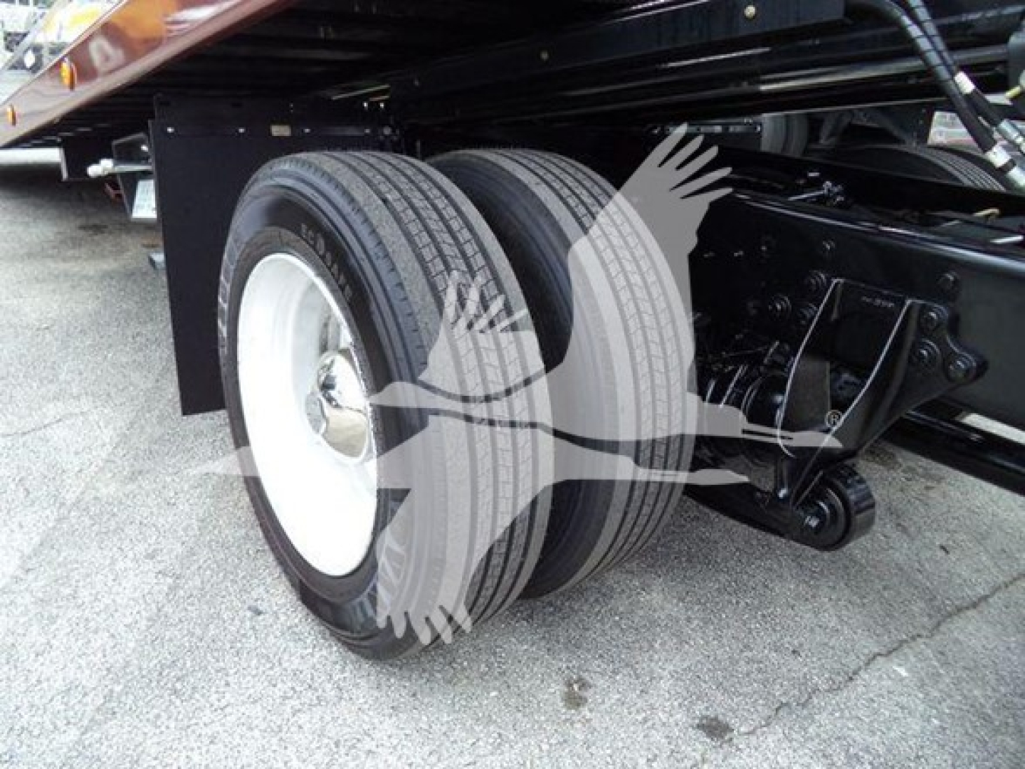 Dual rear wheels on a rollback truck chassis showing tires and suspension components undercarriage.