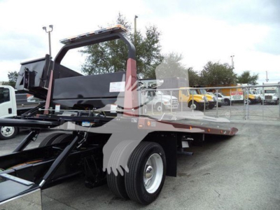 Tow truck rollback bed with hydraulic flats and wheel chocks, side view showing I-beam frame and metal scissor mechanism.