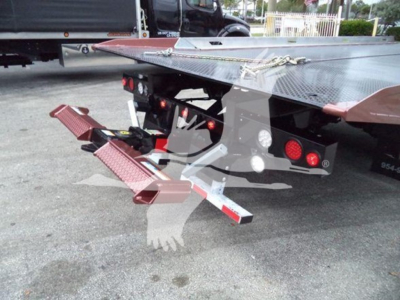 Truck equipment showing a hydraulic rollback bed with side steps and rear bumper, platform and safety chains visible.