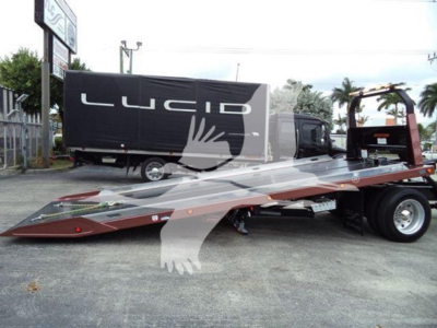 Truck rollback with low-loader trailer attached under a Lucid sign