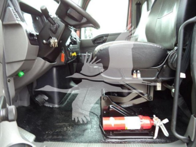 Truck cab interior of a 2020 International MV with a fire extinguisher mounted under the dashboard near the driver seat and pedals visible.