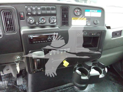 Dashboard of a 2020 International MV rollback truck showing instrument cluster, climate controls, radio, cup holders, and warning labels.