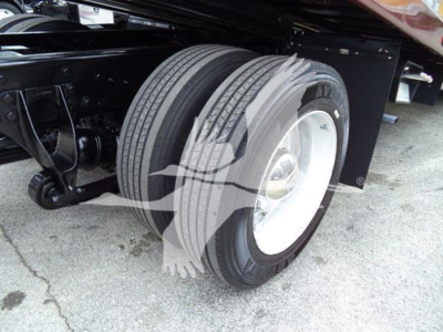 Truck rear dual wheels assembly showing white steel rims and dual tires on a rollback chassis, undercarriage with suspension and frame components visible.