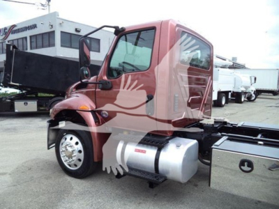 International MV truck tractor with red cab and exposed silver fuel tanks, side view showing cab interior and wheel, rollback category.