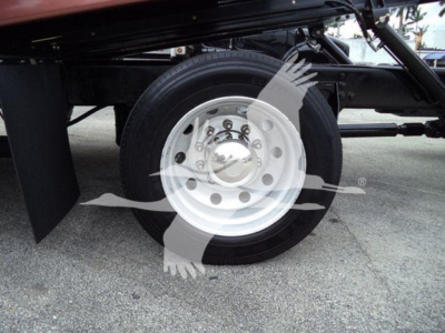 Truck wheel and part of chassis with circular steel wheel hub and tire visible; watermark of a flying bird logo overlaying the center