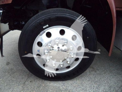 Truck wheel and tire showing polished aluminum hub with lug nuts and circular holes, front fender area visible.