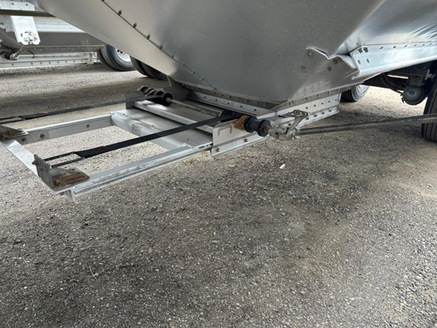 Hopper trailer undercarriage showing structural frame and pivot links of a 2024 Timpte Super Hopper; metal framing and hitch area visible.