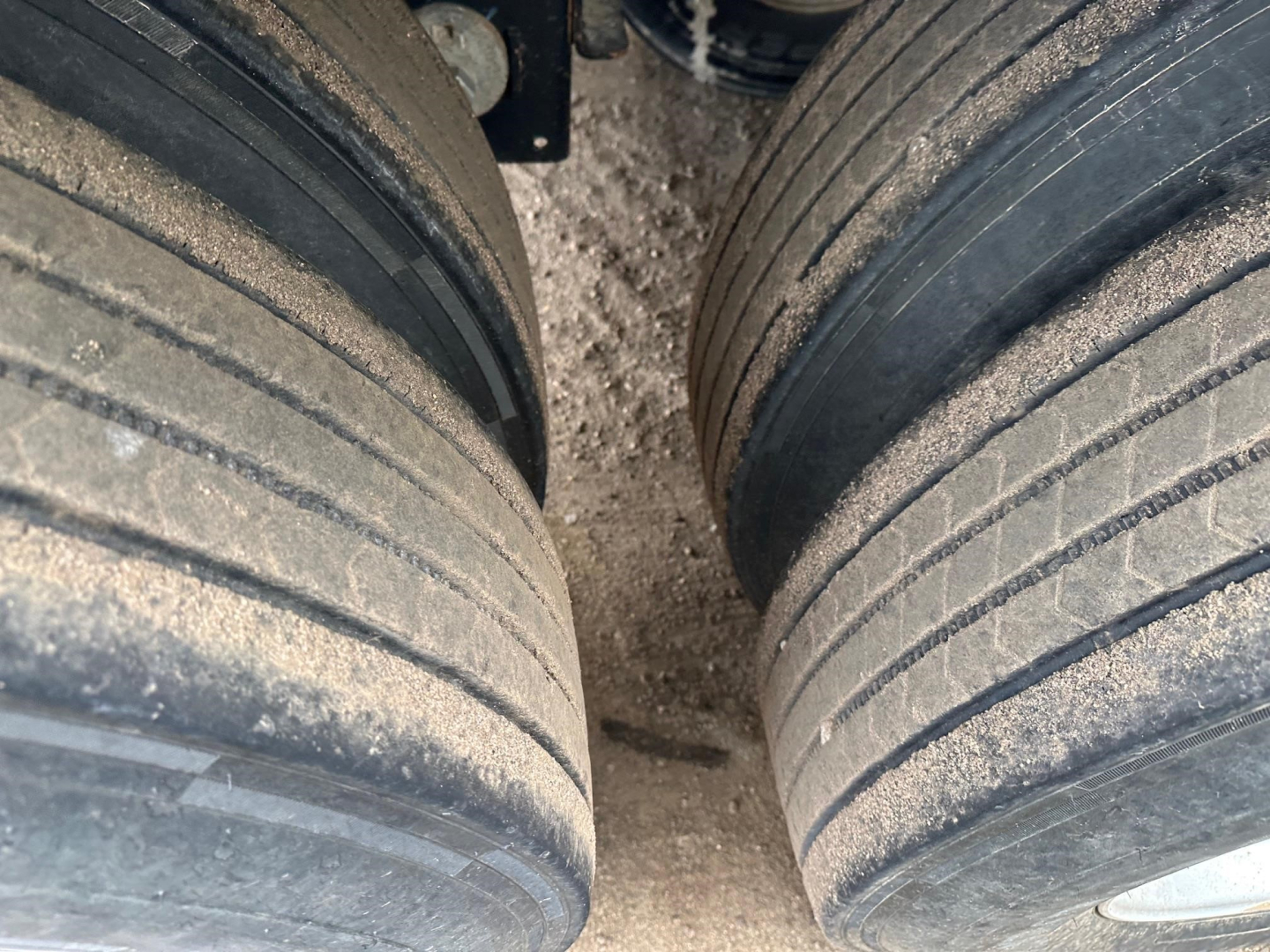 Trailer axle dual tires with dirt; sidewalls show wear and tread grooves visible in the image.