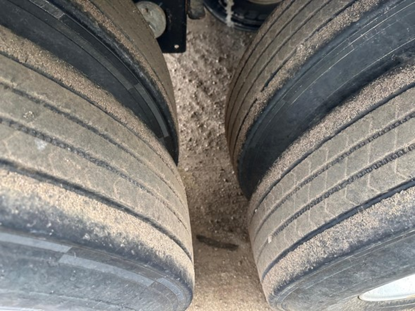 Two large rear tires of a Timpte Super Hopper trailer viewed from between wheels, showing dirt on tires and wheel hubs.